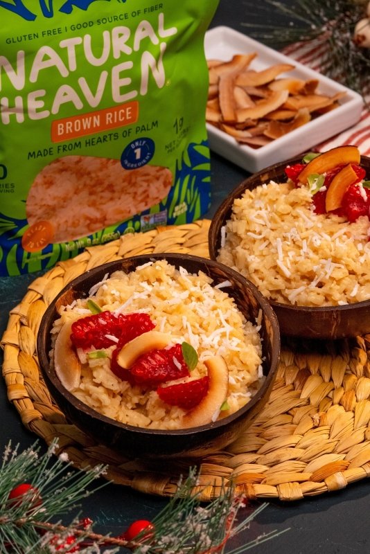 Creamy holiday rice dessert made with hearts of palm brown rice, coconut milk, cinnamon, and festive toppings like coconut, cranberries, or pistachios.