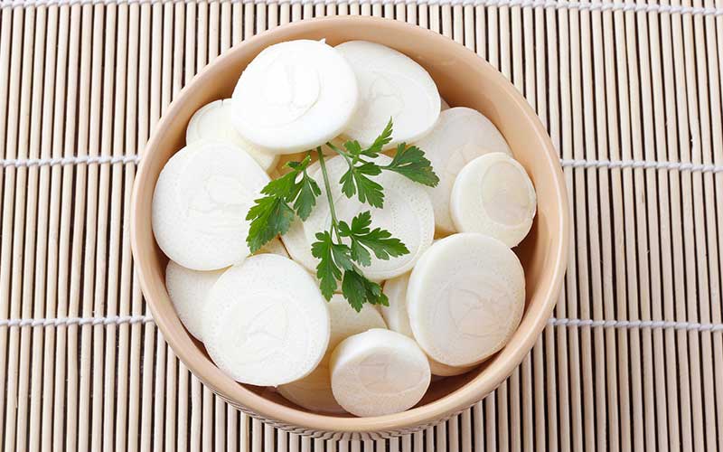 Sliced palm heart palmetto salad in ceramic bowl over rustic wooden table. low carb food