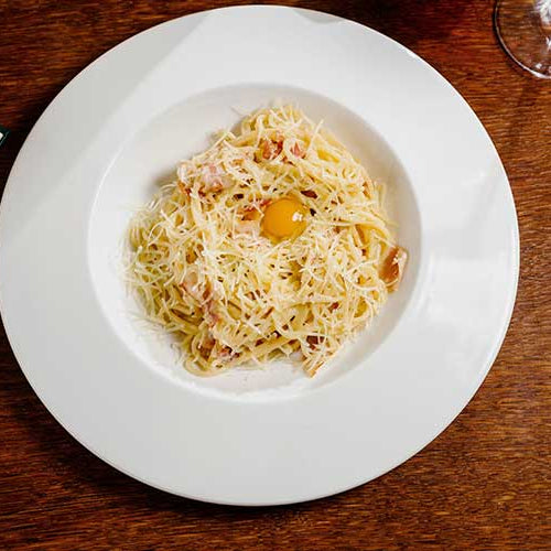 Spaghetti with cheese and egg on a white plate