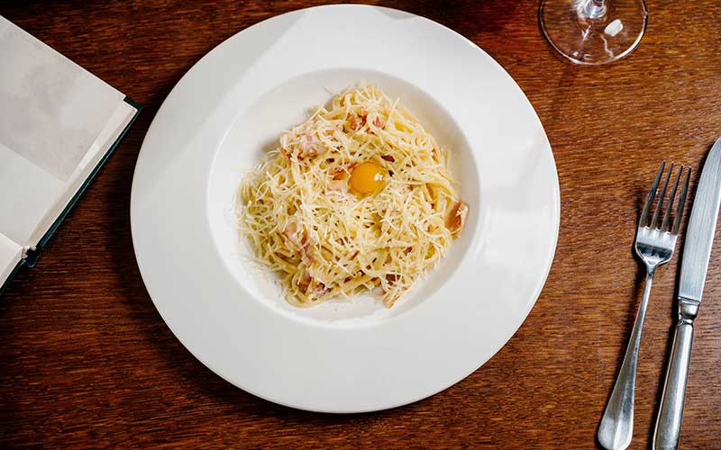 Spaghetti with cheese and egg on a white plate